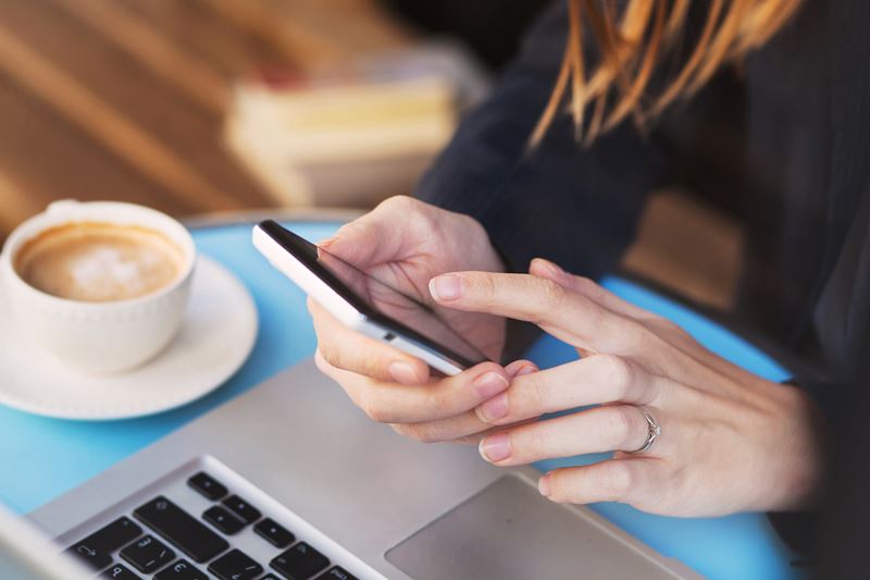 person with coffee, mobile device and laptop