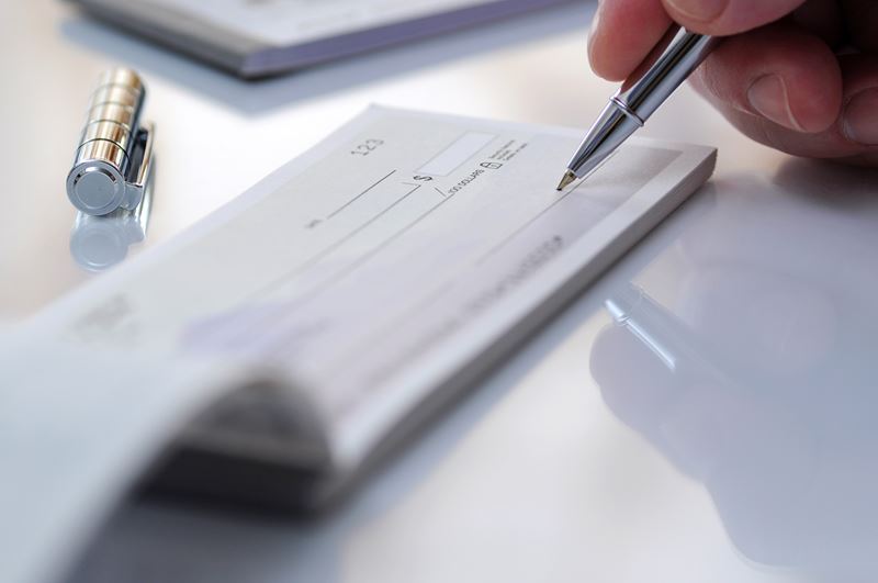 person writing on a checkbook