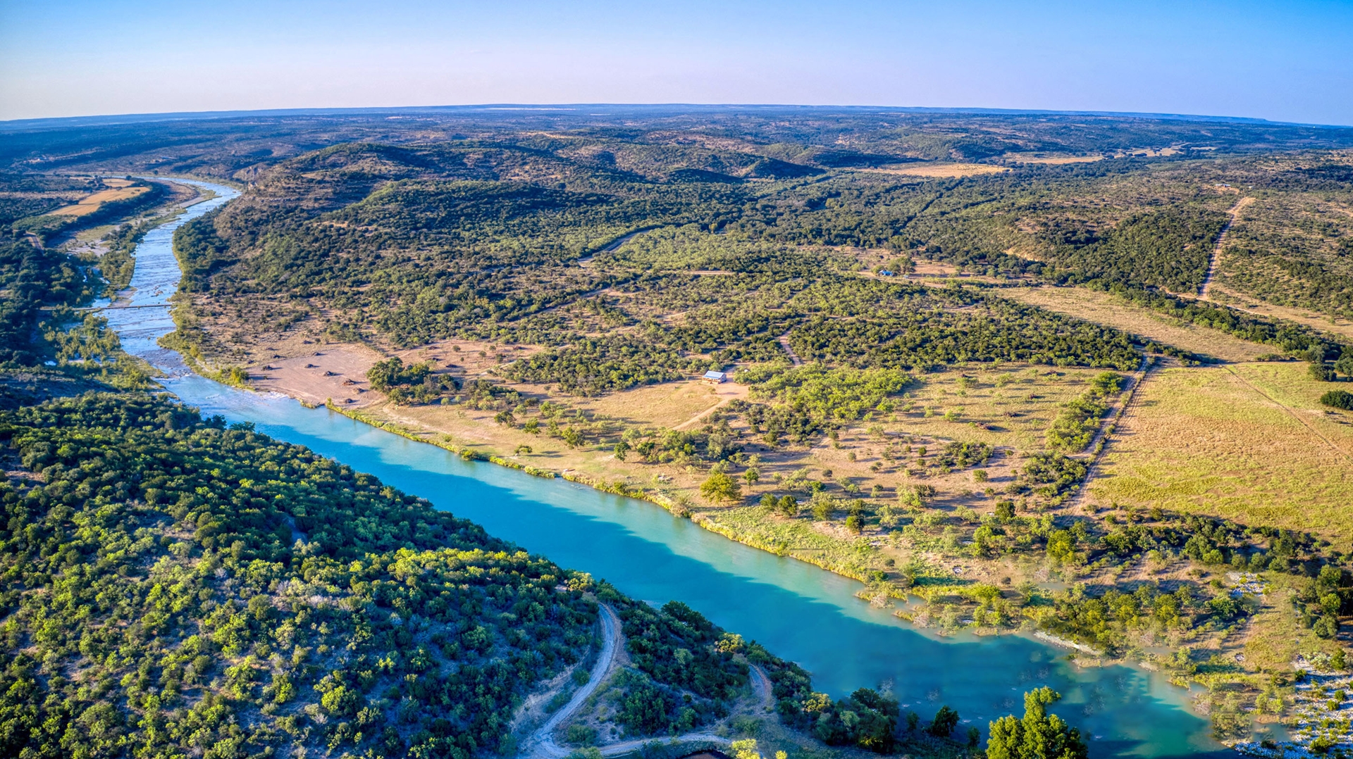 river with green trees and fields on both sides